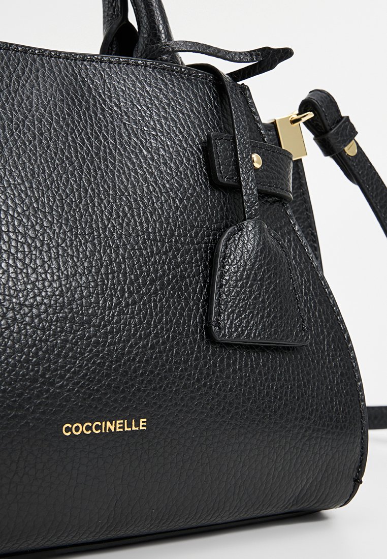 Borsa a mano in pelle nera con finitura testurizzata, hardware color oro e una piccola tasca laterale. Logo "Coccinelle" impresso in oro.