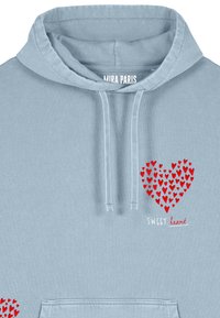 Svetlomodrá mikina s kapucňou, na ktorej je červený srdcový motív z menších srdiečok a text "SWEET heart" v červenej a bielej farbe. Mäkka látka, štýl na prevliekacie.