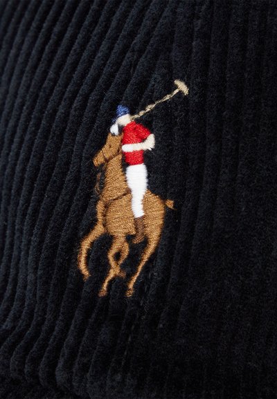 Tecido de corduroy preto com nervuras verticais, apresentando um jogador de polo bordado em cima de um cavalo nas cores castanho, vermelho, branco e azul.