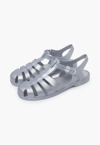 Gray plastic sandals with an open design, featuring horizontal and vertical slits, back strap, and adjustable buckle detail.