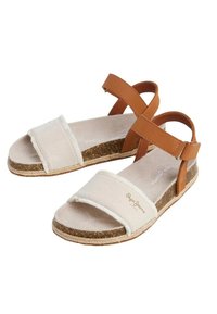 Sandali con cinturini in pelle color cuoio, parte superiore in tela beige e suola in sughero. Presentano cinturini regolabili alla caviglia e un design piatto.