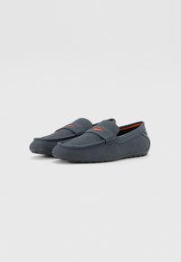 Mørkeblå slip-on sko laget av teksturert stoff, med mesh-design, oransje detaljer og en lavprofil gummisåle.