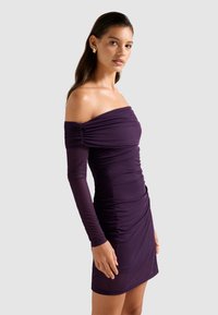 Μωβ φόρεμα με ανοικτούς ώμους και μακριά μανίκια, με ρυτιδωτή υφή, εφαρμοστό σχέδιο και μήκος πάνω από το γόνατο. Λείο ύφασμα με λαμπερό φινίρισμα.