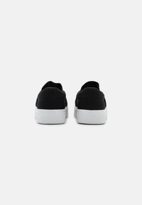 Schwarze Leinenschuhe mit minimalistischen Design, ausgestattet mit einer weißen Gummisohle, runder Zehenpartie und ohne sichtbare Marken oder Muster.