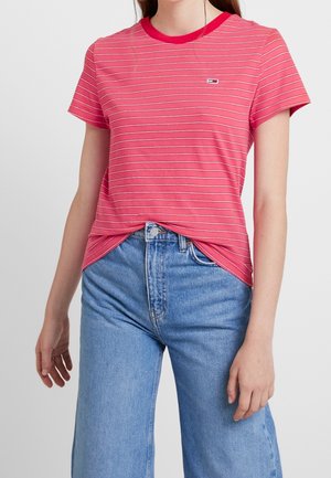 Czerwono-biała koszulka w paski z krótkim rękawem, okrągłym dekoltem i małą naszywką z logo, zestawiona z wysokim stanem niebieskich dżinsów.