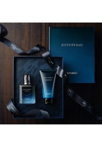 Sættet inkluderer en mørkeblå boks med teksten "INTUITION", en rektangulær flaske i sort og blå, og en blå tube med sort låg, alle med marineblå bånddetaljer.
