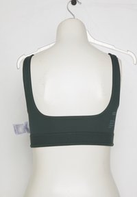 Black sports bra with wide straps displayed on white mannequin back, hanging on white plastic hanger against white background.