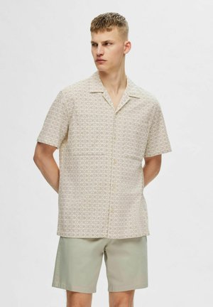 Kortærmet skjorte med knaplukning i lysebeige med blomsterprint, parret med lysegrønne shorts, der har en afslappet pasform og en afslappet krave.