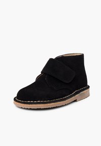 Bottines en daim noir avec une sangle auto-agrippante, bout arrondi et semelle extérieure marron clair. Détails cousus le long du bord de la semelle.