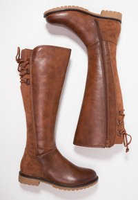 Brązowe botki do kolan z wykończeniem z gładkiego i zamszowego materiału, z suwakiem po boku oraz dekoracyjnymi sznurówkami z tyłu. Gumowa podeszwa zapewniająca przyczepność.