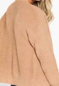 Suéter beige con una textura acogedora y esponjosa, con sutilezas de hilo metálico. El diseño incluye una silueta simple y relajada.
