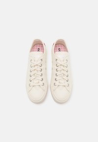 Bílé plátěné tenisky s kovovými očky, plochými tkaničkami a texturovanou gumovou podrážkou. Interiér je zdobený růžovým kostkovaným vzorem.