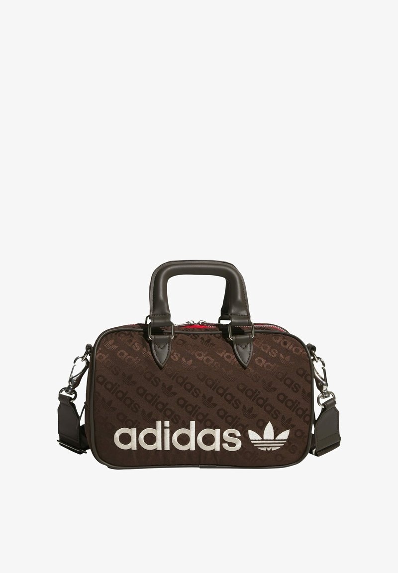 Brown fabric bag featuring repeating adidas logo pattern, leather accents, dual top handles, and a detachable shoulder strap. Red zipper detail.