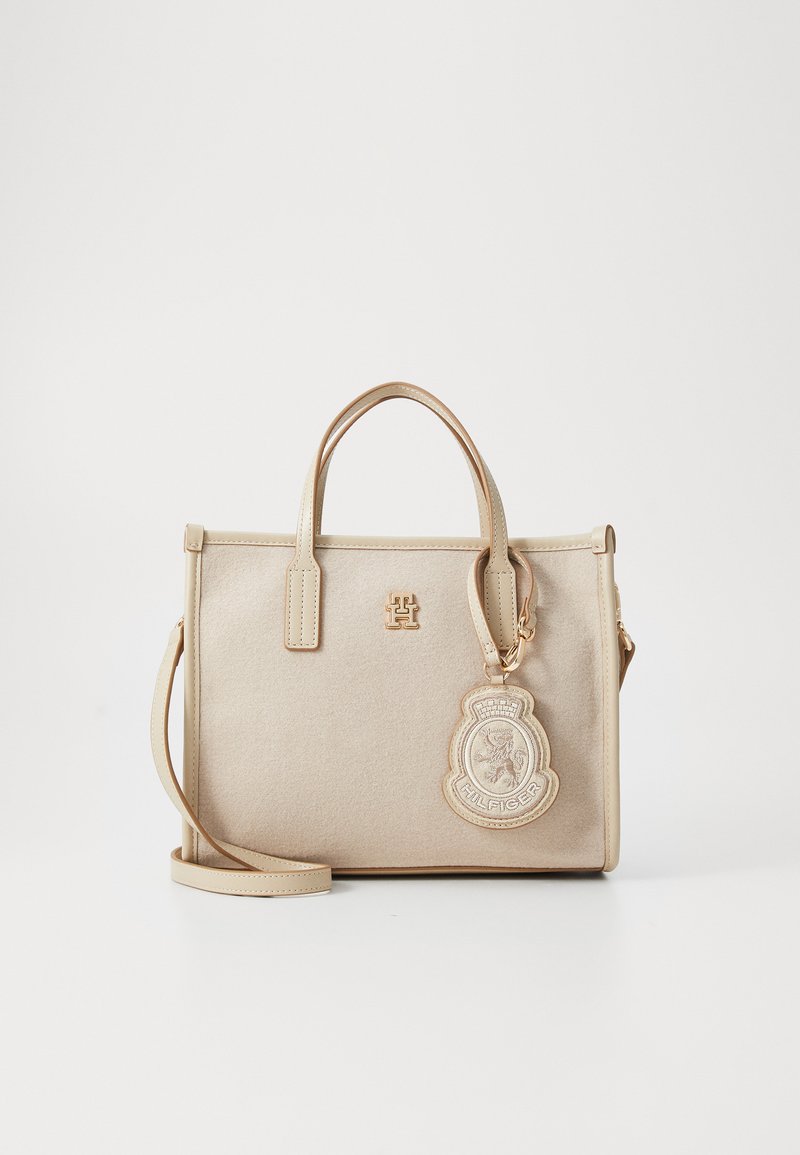 Bolsa bege com um design estruturado, feita de um material texturizado. Apresenta duas alças, uma alça de ombro removível e um charm com o logótipo.