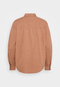 Camicia marrone a maniche lunghe in tessuto intrecciato. Presenta un colletto classico e polsini con bottoni. Il retro è semplice con un orlo curvo.