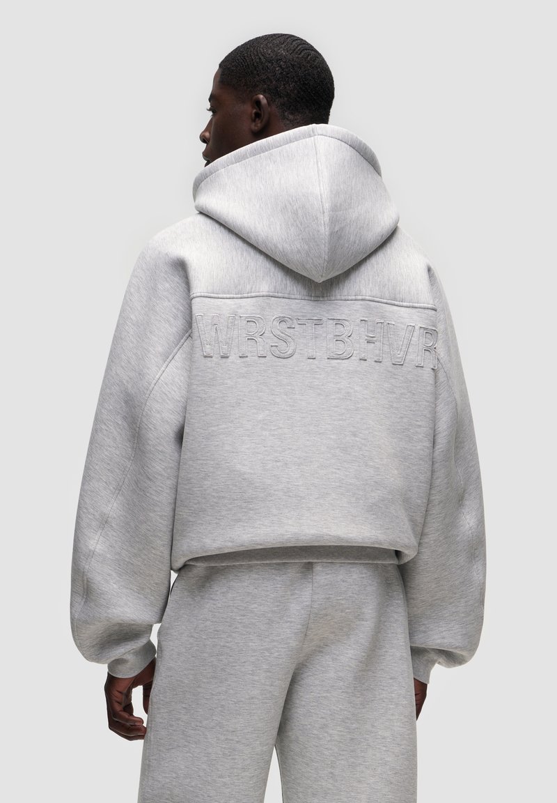Felpa cropped grigio chiaro con una vestibilità oversize, dotata di cappuccio e testo in rilievo "WRSTBHV" sul retro. Realizzata in tessuto morbido e testurizzato.