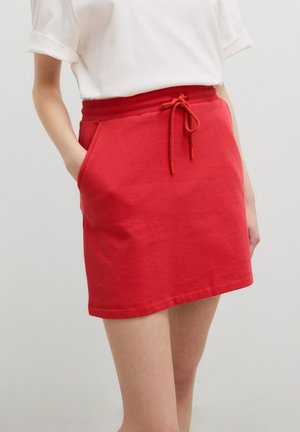 Rode katoenen rok met een elastische tailleband en trekkoord, voorzien van twee zijzakken en een eenvoudige, rechte snit.