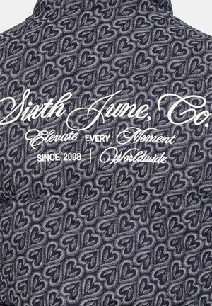 Tissu à motifs bleus avec des cœurs entrelacés ; nom de la marque et slogan brodés en blanc dans la partie supérieure.