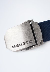 Boucle de ceinture en métal avec "PME LEGEND" gravé, fixée à une sangle en tissu texturé de couleur bleu marine. La boucle présente un design rectangulaire et angulaire.