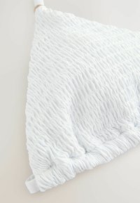 Weißes Kissen mit strukturiertem, gerafftem Stoff. Verfügt über eine dreieckige Form und elastische Kanten, die subtile Dimension und Details hinzufügen.