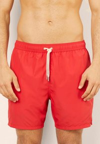 Bañador rojo hecho de un tejido ligero y resistente al agua. Cuenta con una cinturilla elástica con cordón y bolsillos laterales.