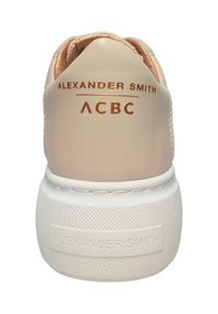 Sneaker beige con tomaia in pelle liscia, dettagli in oro rosa e suola in gomma bianca texturizzata. Il marchio sul tallone dice "Alexander Smith ACBC."
