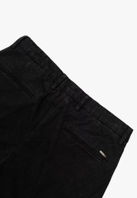 Pantaloni neri con una texture liscia, dotati di una vita e due tasche posteriori con zip. Dettagli di cucitura discreti vicino alle tasche.