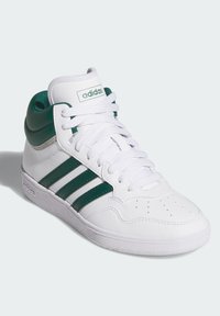 Wysokie sneakersy z białej syntetycznej skóry, zielonymi akcentami, trzema zielonymi paskami po boku oraz teksturowaną gumową podeszwą.