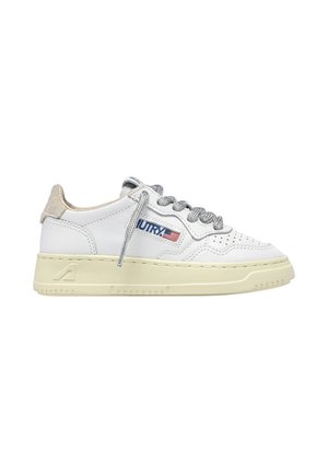 Baskets basses blanches avec lacets gris, bout perforé, semelle beige, languette de talon en daim et logo du drapeau américain sur le côté.