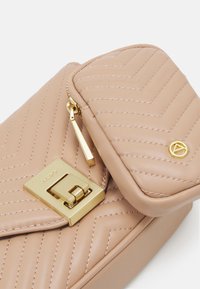 Borsa in pelle beige trapuntata con chiusura a lucchetto dorato, dotata di linguetta e cuciture decorative a motivo chevron. Accentuata da un logo dorato.