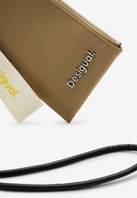 Busta marrone realizzata in materiale morbido, con logo "Desigual." in argento, cinturino beige e cinturino per il polso nero testurizzato.