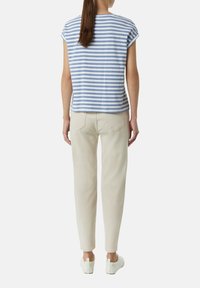 Blau-weiß gestreiftes kurzärmliges Oberteil, kombiniert mit beigen Hosen und weißen Sneakers. Das Oberteil hat einen runden Halsausschnitt und einen lockeren Sitz.