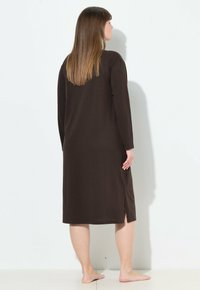 Abito marrone a maniche lunghe con una vestibilità comoda, caratterizzato da spacchi laterali per la libertà di movimento, realizzato in un tessuto morbido, raggiungendo la lunghezza a metà polpaccio.