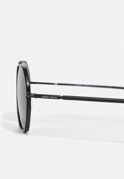 Black sunglasses with a rounded shape, featuring thin metal frames. The arm is marked with "Giorgio Armani" in white lettering.