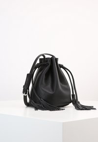 Borsa a secchiello in pelle nera con tracolla regolabile, apertura arricciata e lunghe frange su entrambi i lati. Texture liscia e design minimalista.