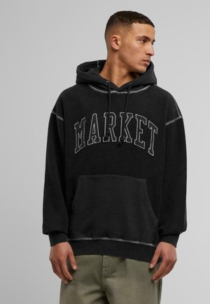 Schwarzer Kapuzenpullover mit "MARKET" in Weiß auf der Brust. Mit einer Vordertasche und kontrastierenden Nähten. Weicher, strukturierter Stoff.
