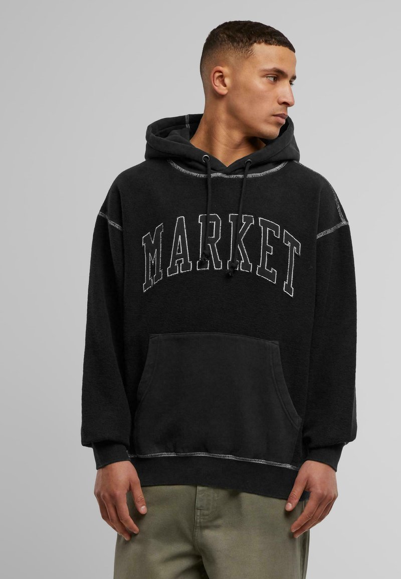 Svart hettegenser med "MARKET" trykket i hvitt på brystet. Har en frontlomme og kontrastsøm. Myk, strukturert stoff.