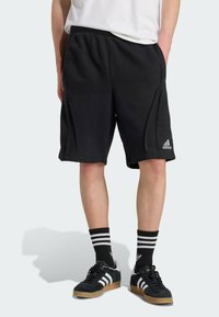 Crne kratke hlače od mekanog materijala, s bočnim šavovima, elastičnom strukom i Adidas logotipom na lijevoj nozi.