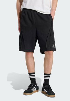 Črne kratke hlače iz mehke tkanine, s stranskimi šivi, elastičnim pasom in logotipom Adidas na levi nogi.