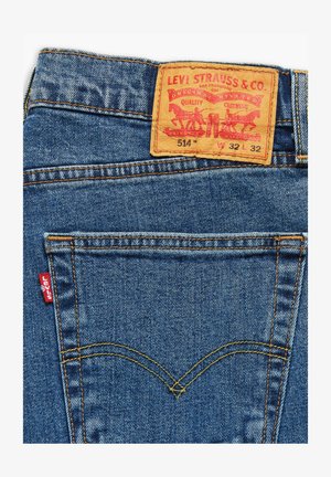 Levi's 514 Jeans aus dunkelblauem Denim, mit einem hellbraunen Lederpatch auf der Rückseite, einem roten Etikett auf der linken Tasche und kontrastierenden gelben Nähten.