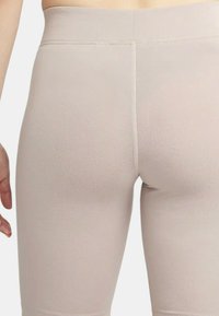 Ljust beige högmidjade leggings med en mjuk textur, med sömmar längs mitt- och sidosemmarna, figurnära design och längd till mitten av vaden.