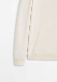 Manche longue de pull crème avec poignets et ourlets côtelés sur un fond blanc uni.