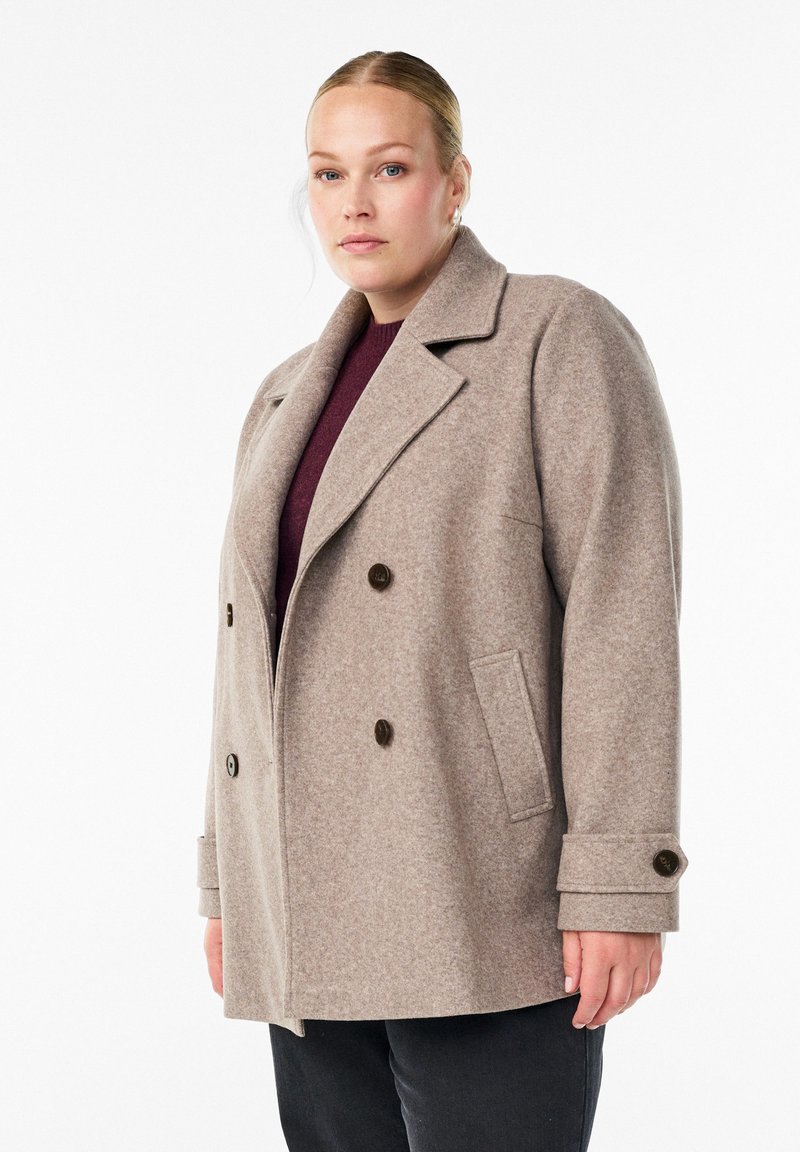 Double-breasted coat in light brown wool blend, featuring notched lapels, two front pockets, and dark buttons, with a relaxed fit.