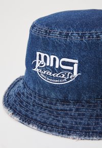 Denim šešir s rubom od niti, s bijelim izvezenim logom koji sadrži natpis "mncl Paradise Disco Dancing Club". Tamnoplava boja.