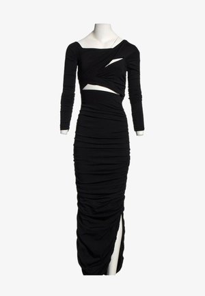 Longue robe noire froncée avec manches longues, découpes asymétriques au niveau de la poitrine et de la taille, et une fente haute devant sur un mannequin blanc.