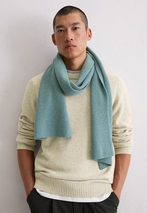 Hellblauer gerippter Schal, der über einen beigen strukturierten Pullover gelegt ist. Weicher Strickstoff mit einem lässigen Design, das einen geschichteten Kragen aufweist.