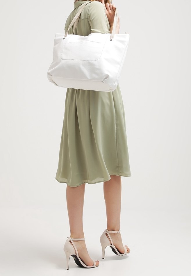 Biała torba na ramię z podwójnymi ramiączkami, gładką teksturą, dużą główną komorą i kieszonką zewnętrzną. Połączona z sukienką do kolan w zielonym kolorze.