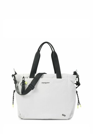 Sac cabas blanc Hedgren avec poignées noires, bandoulière réglable, poches zippées et petit logo devant sur fond uni.