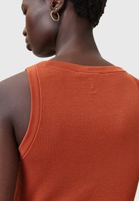 Roestoranje geribbele tanktop met een ronde halslijn, dunne bandjes en een subtiele logo-detail nabij de achternaad. Soepele textuur.