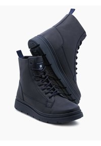 Botas altas de color azul marino hechas de material sintético liso, con punta redonda, cuello acolchado y suela de goma texturizada con sistema de cordones.